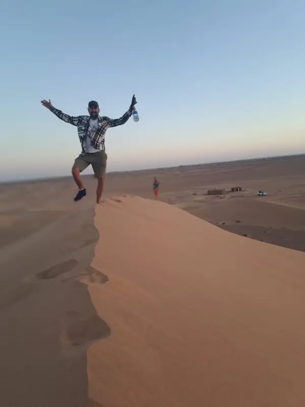 Traveller jumping on a dune