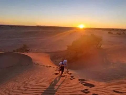 Walking up a dune at sunset